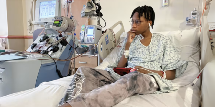 Wedam Minyila spent hours on his phone or sleeping during his stem cell collection, as an apheresis machine drew his blood out of his body, spun out the stem cells and then returned the blood back into his veins.Jason Kane / NBC News